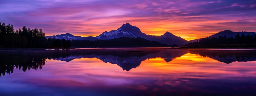 a vibrant sunset paints the sky in bold hues of orange and purple, illuminating a lone silhouette of a majestic mountain reflecting in a serene lake below.